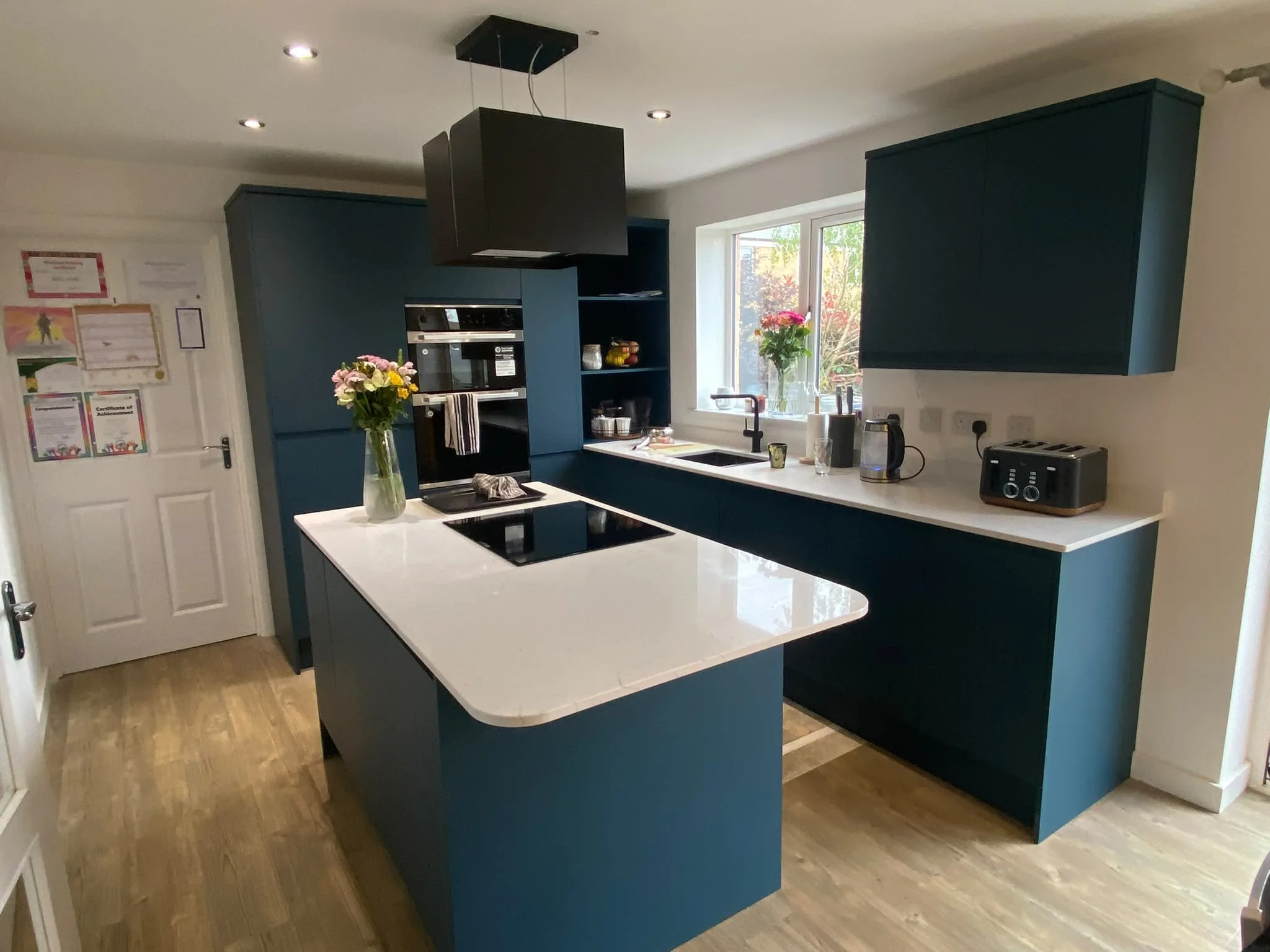 Completed fitted kitchen with dark teal cabinetry and a central island