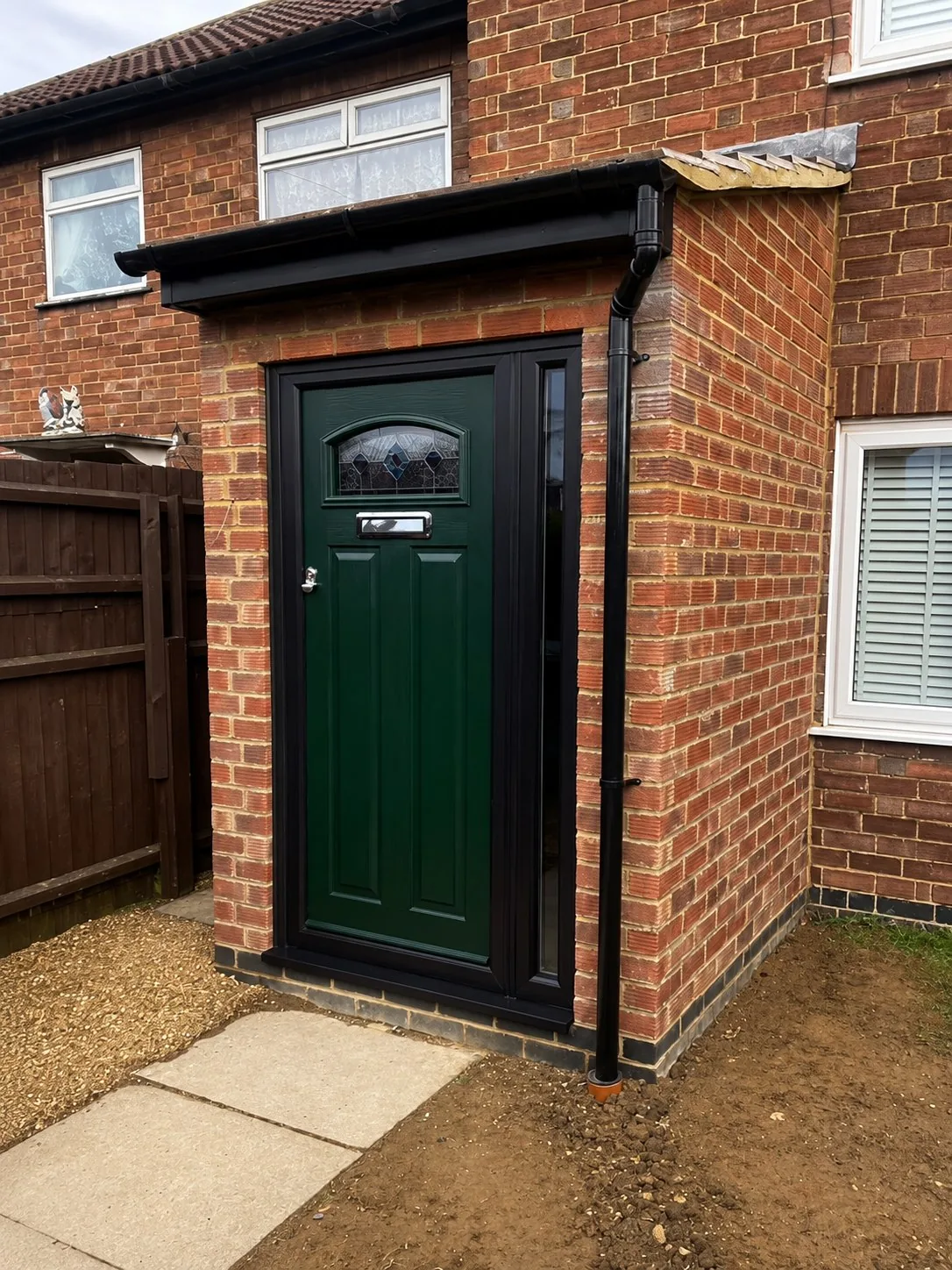 New brick entrance porch with a green composite door and black roofline