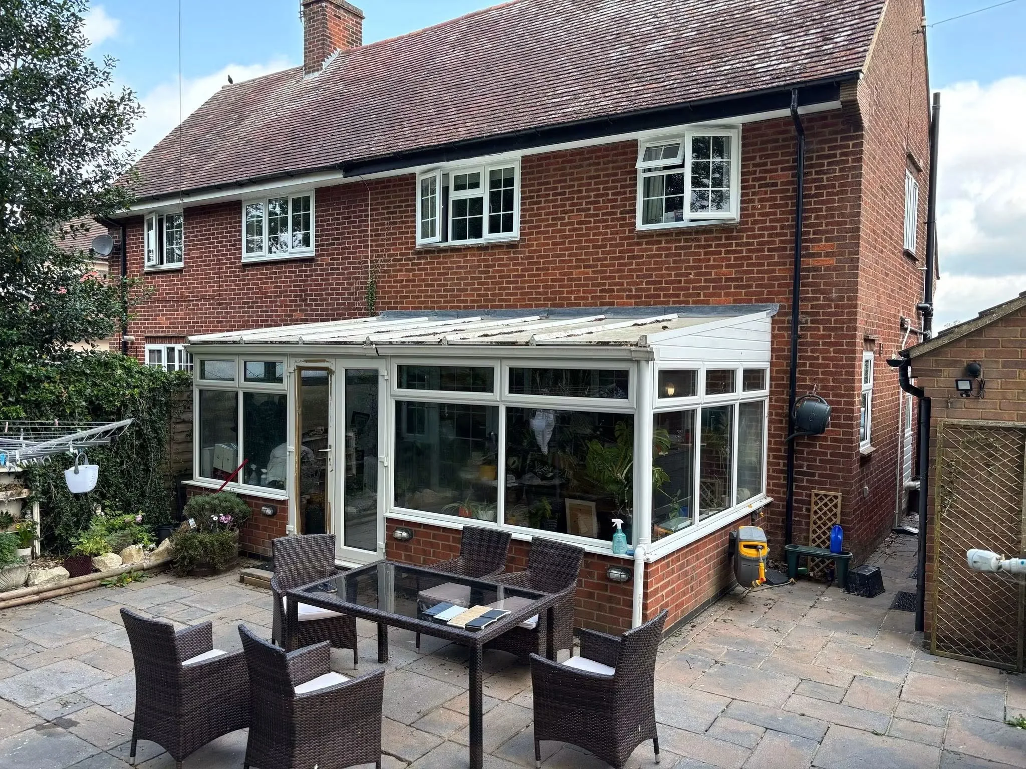 The original white conservatory before renovation, with a shallow polycarbonate roof