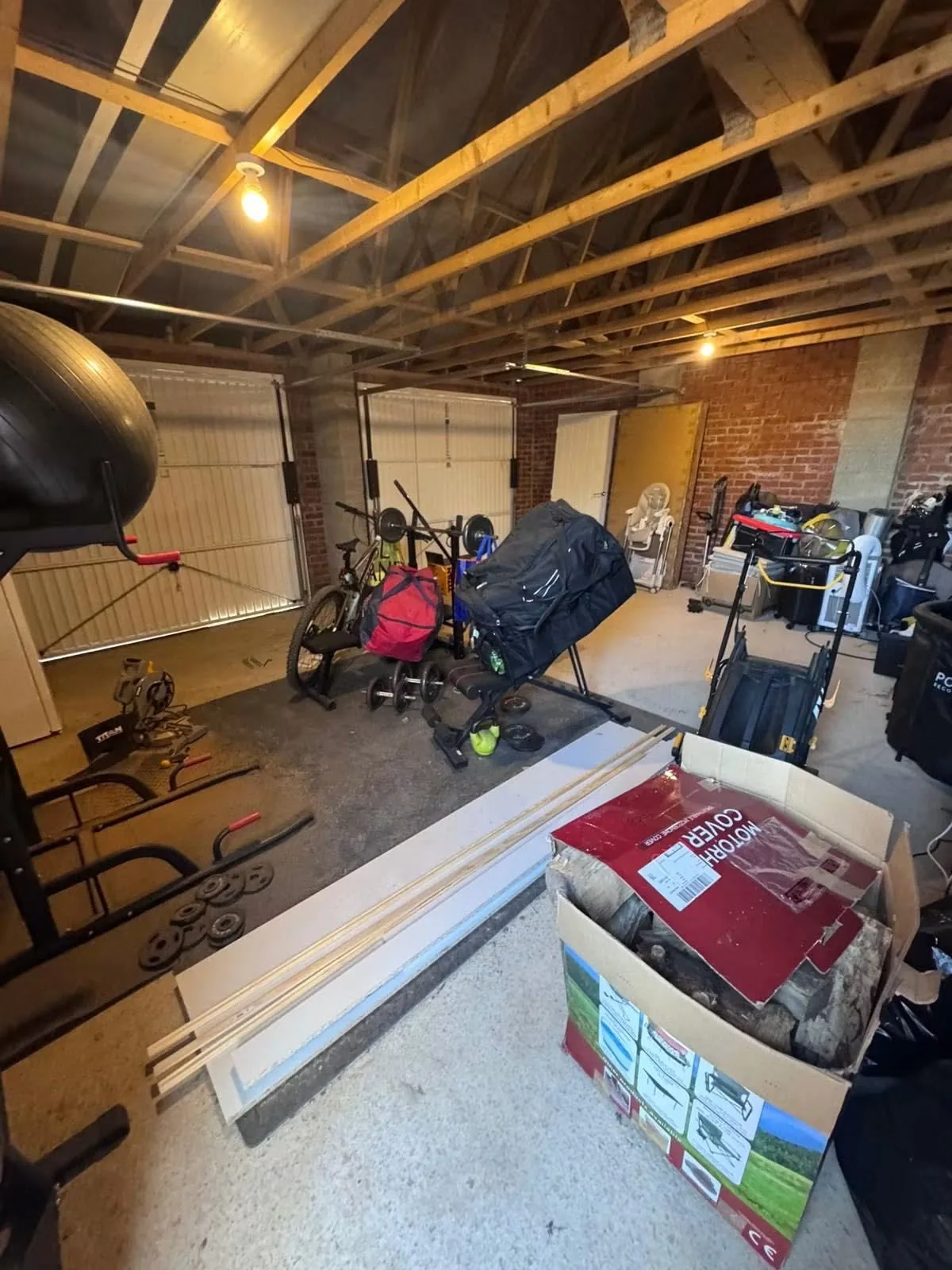 The double garage before conversion with exposed roof structure, brick walls and stored equipment