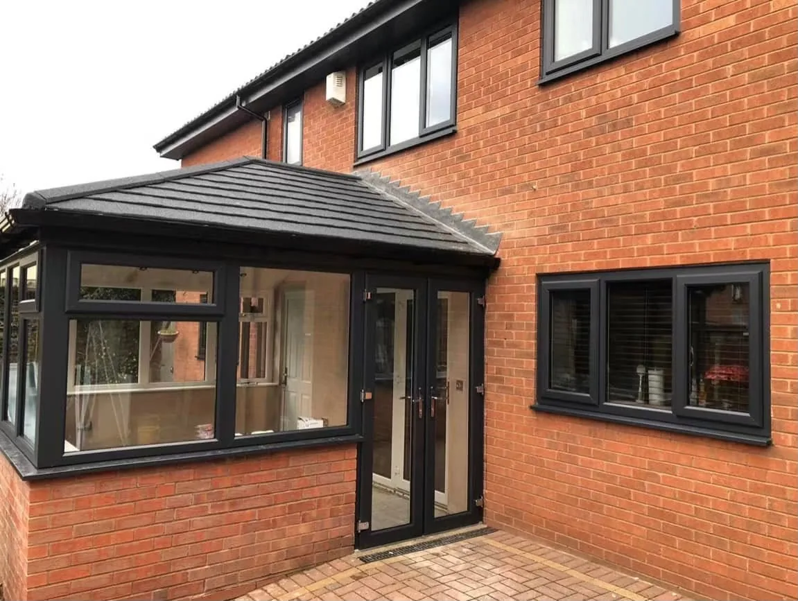 Conservatory renovation with a tiled warmer roof and black window frames