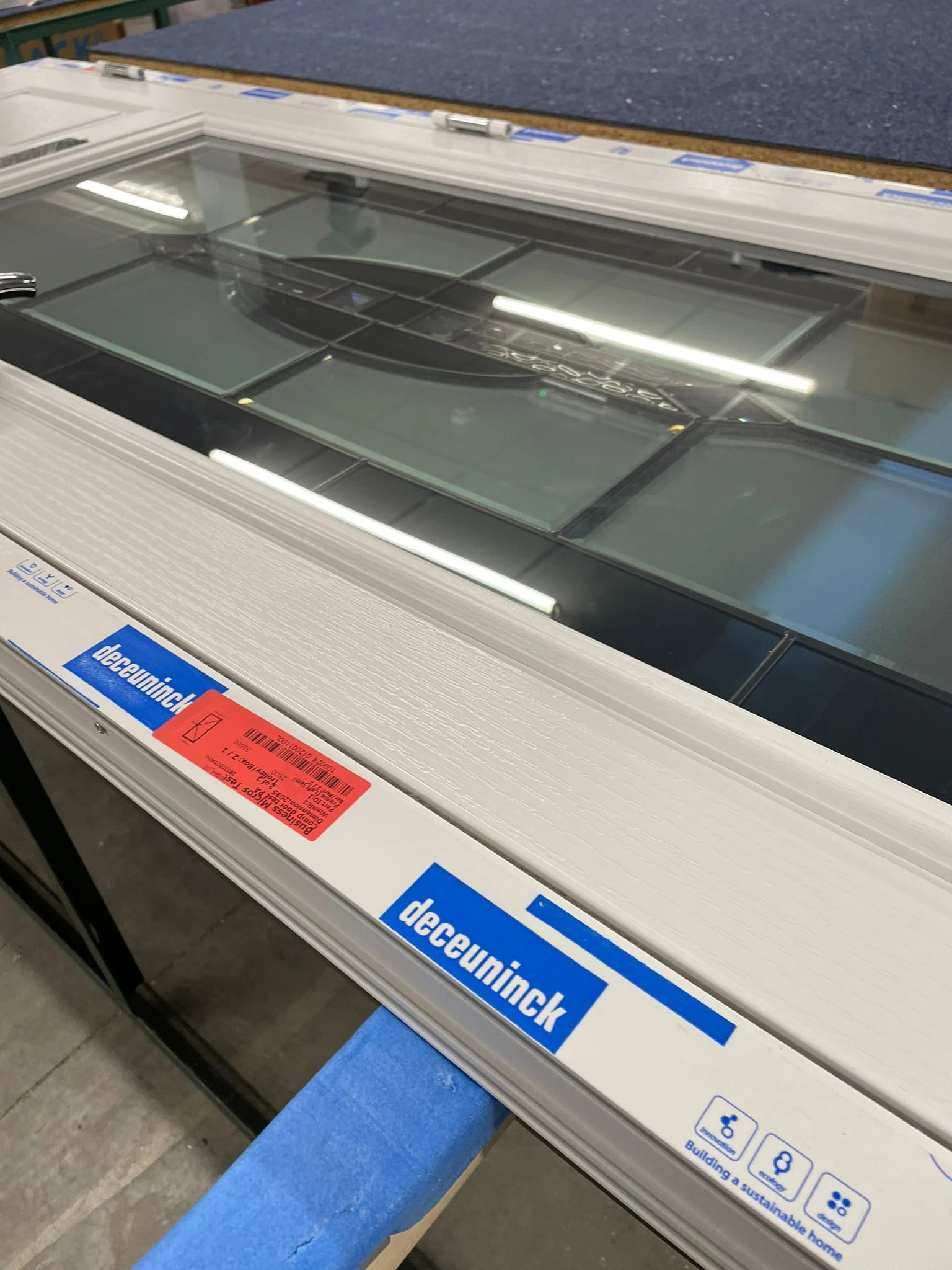 Decorative glazed door panel being assembled within the frame during manufacture