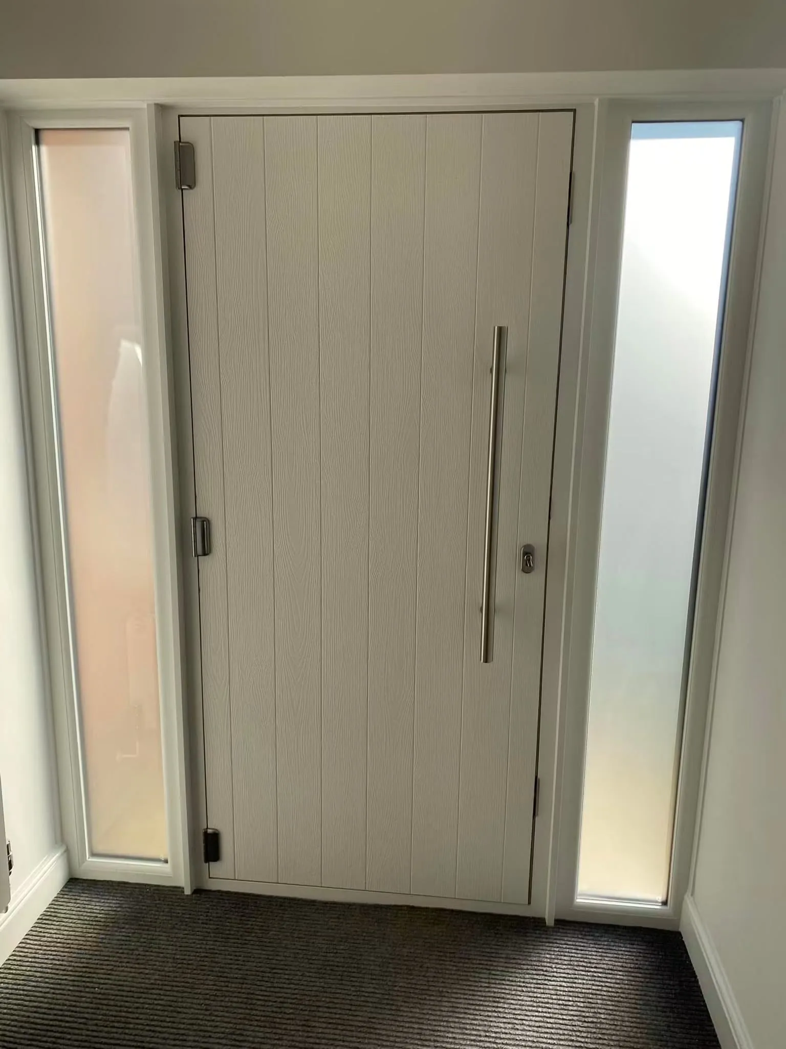 Long stainless-steel pull handle fitted to an entrance door