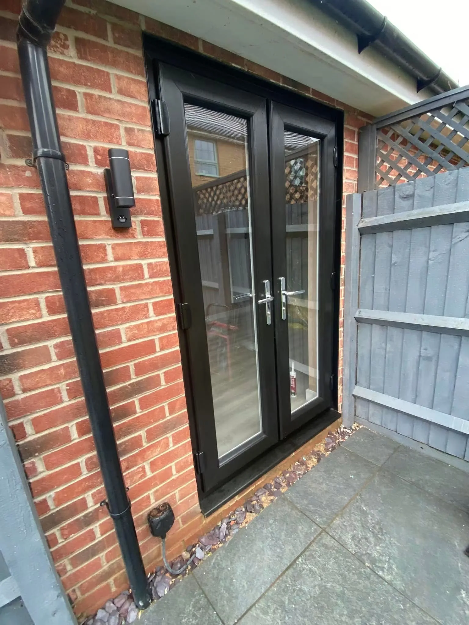 Black French doors with matching handles installed in a brick garage conversion