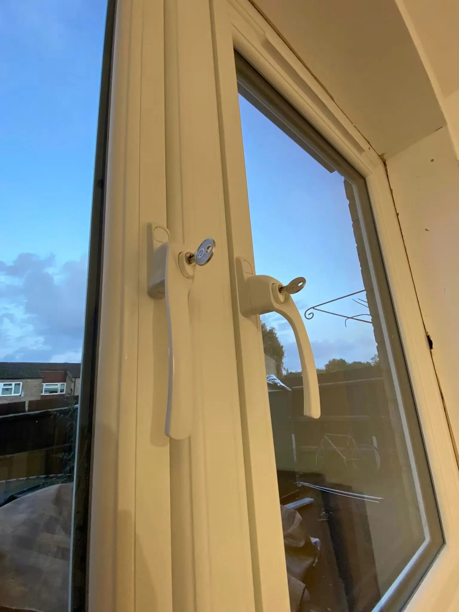 Close-up of locking window handles and a safety restrictor on white casement windows